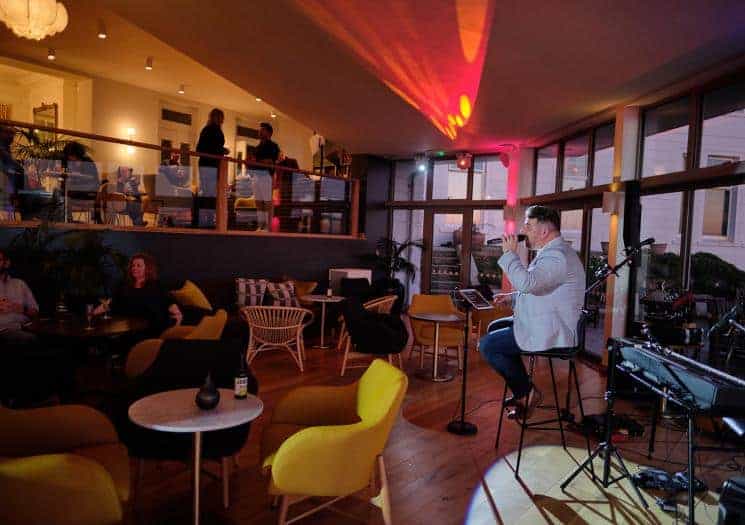Man sitting on a stool while singing in a café