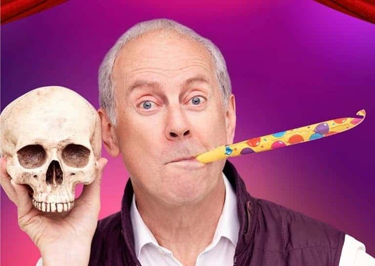 Comedy artist Gyles Brandreth holding a skull