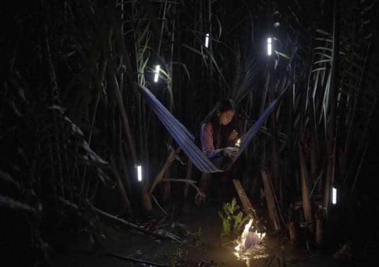 Video stills by Artist Thao Nguyen Phan showing a girl holding a candle while sitting on a hammock
