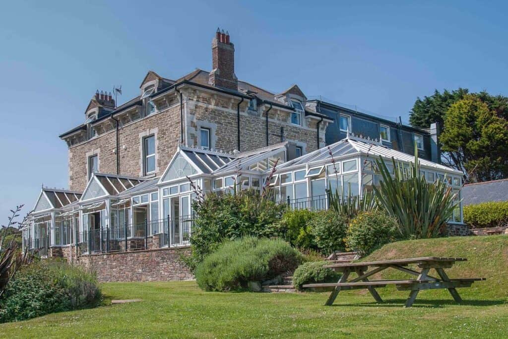 Victorian house with conservatory and garden in sunshine.