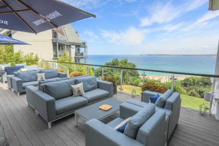 Seaside terrace with sofas overlooking beach and ocean.