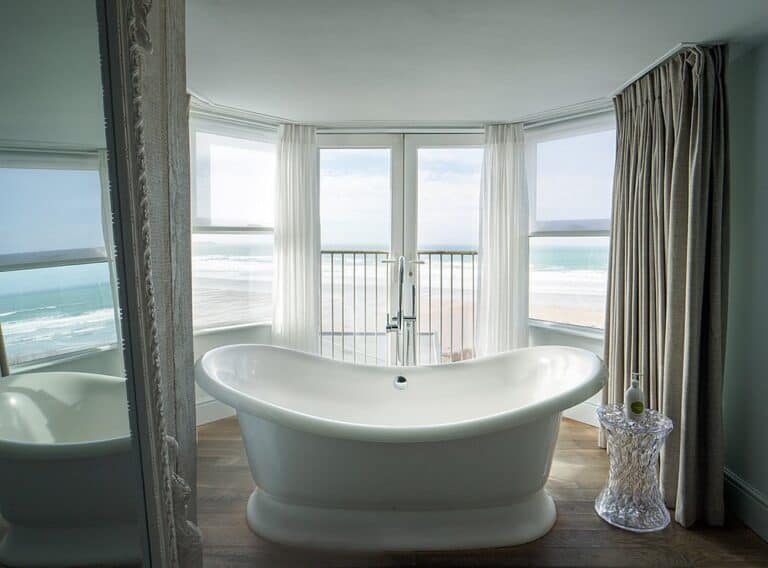 Beach view from elegant bathroom with freestanding tub.