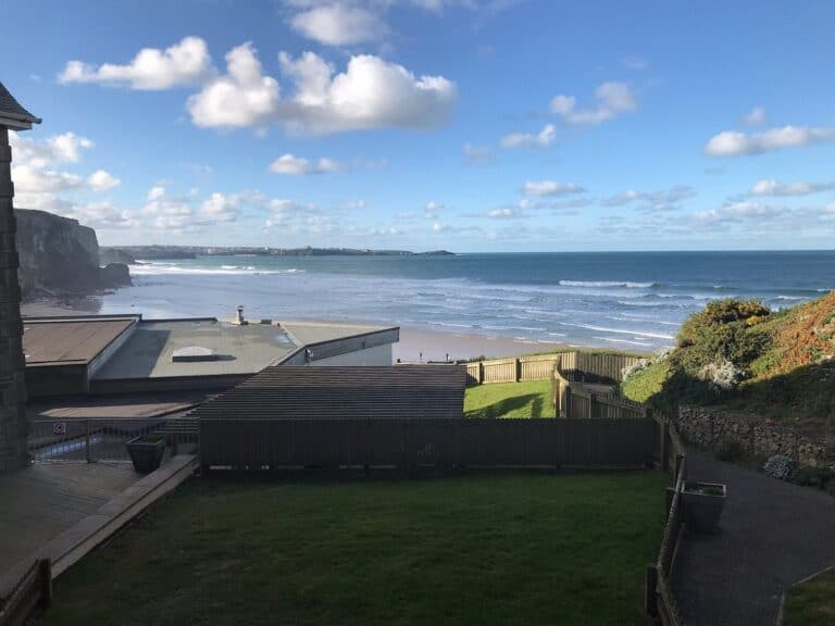 Coastal view with beach, cliffs, and blue sky.